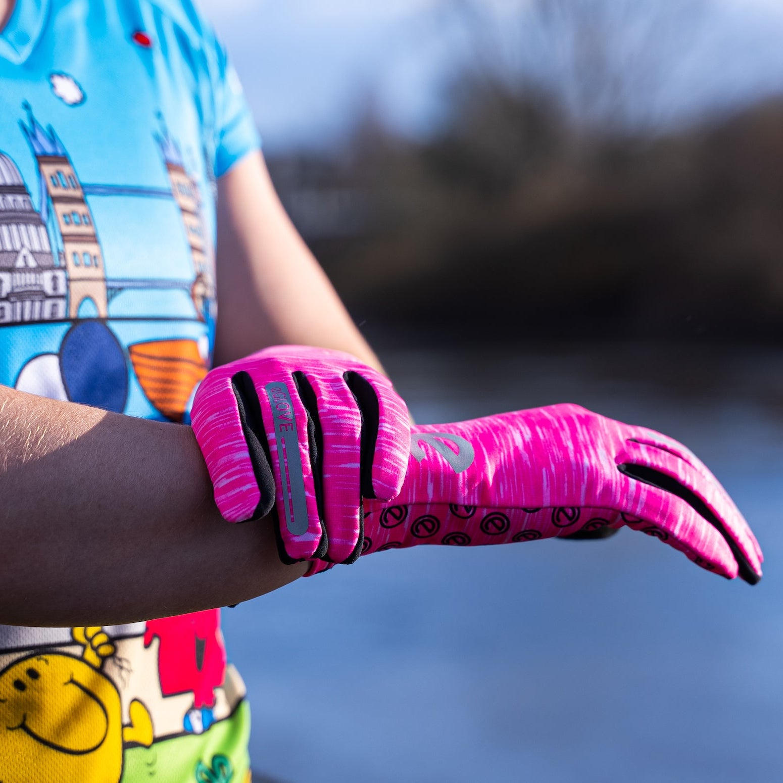 Pink touchscreen running gloves worn by a runner outdoors during training.