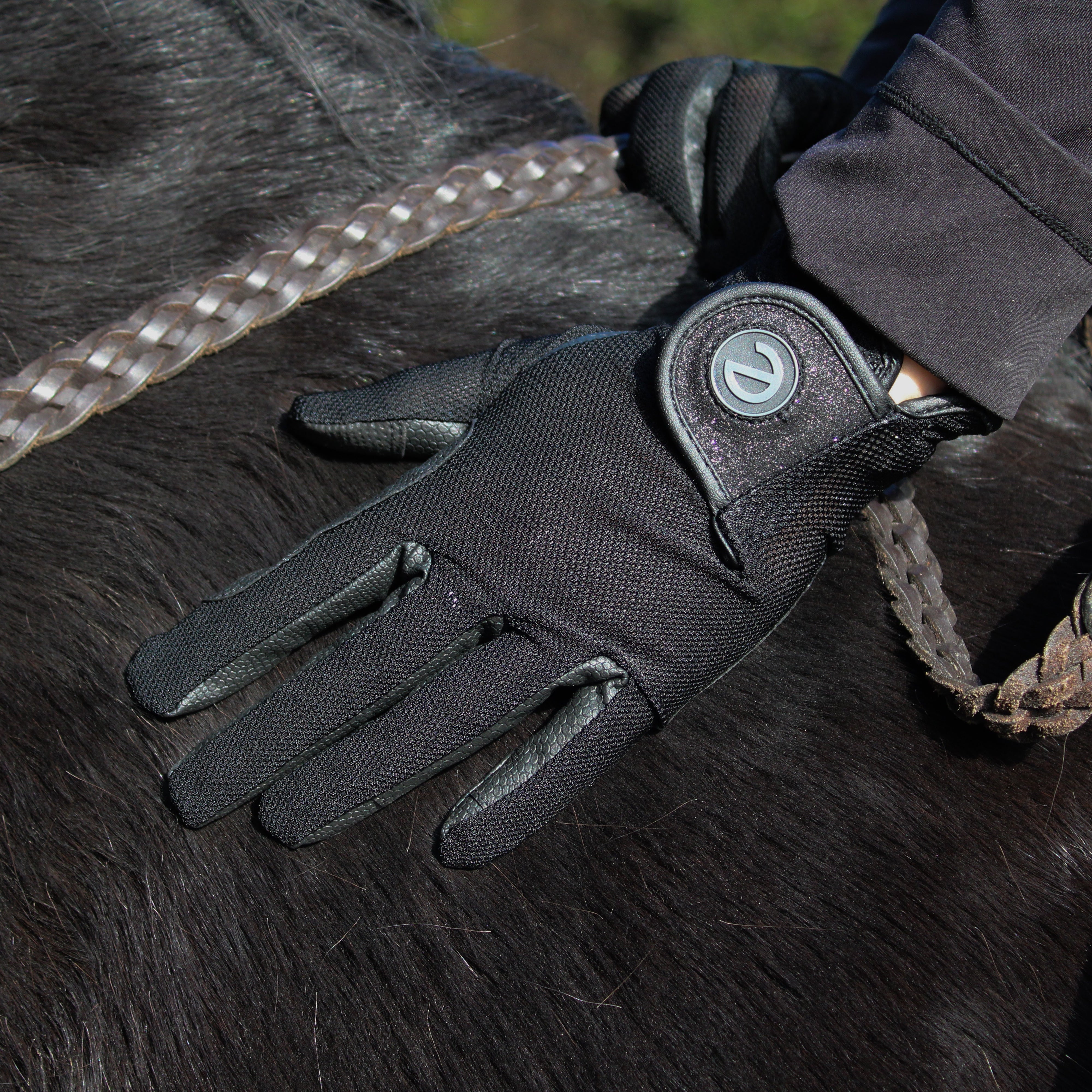 Close-up of black touchscreen horse riding glove with grip palm and secure wrist closure.